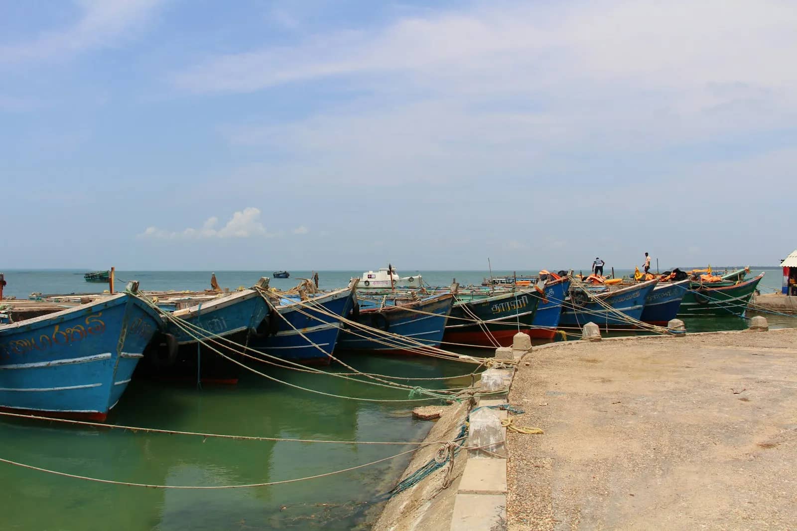 கற்காரை இறங்குதுறையில் கட்டப்பட்ட நீல மரப் படகுகள்